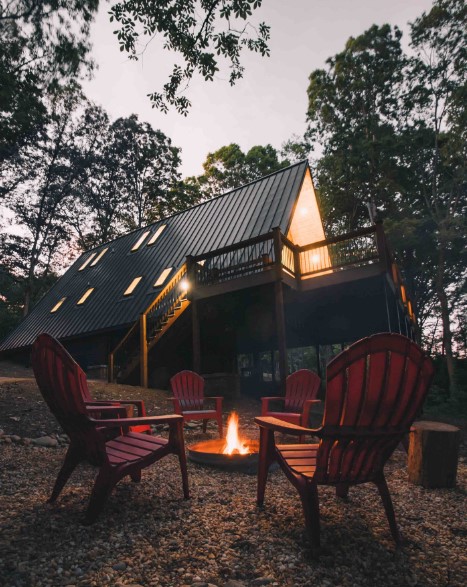 fire pit outside the cabin with red chairs around it