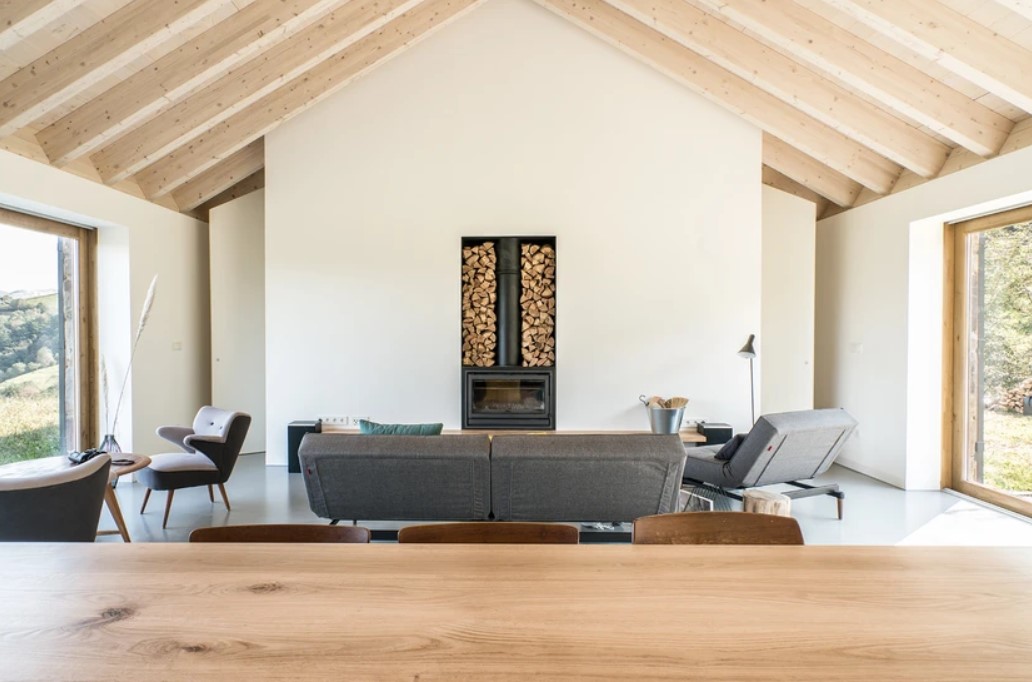 gray couch and a fireplace with stacked wood in the living room