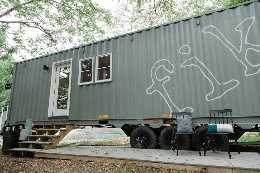 Green shipping container home with a front porch