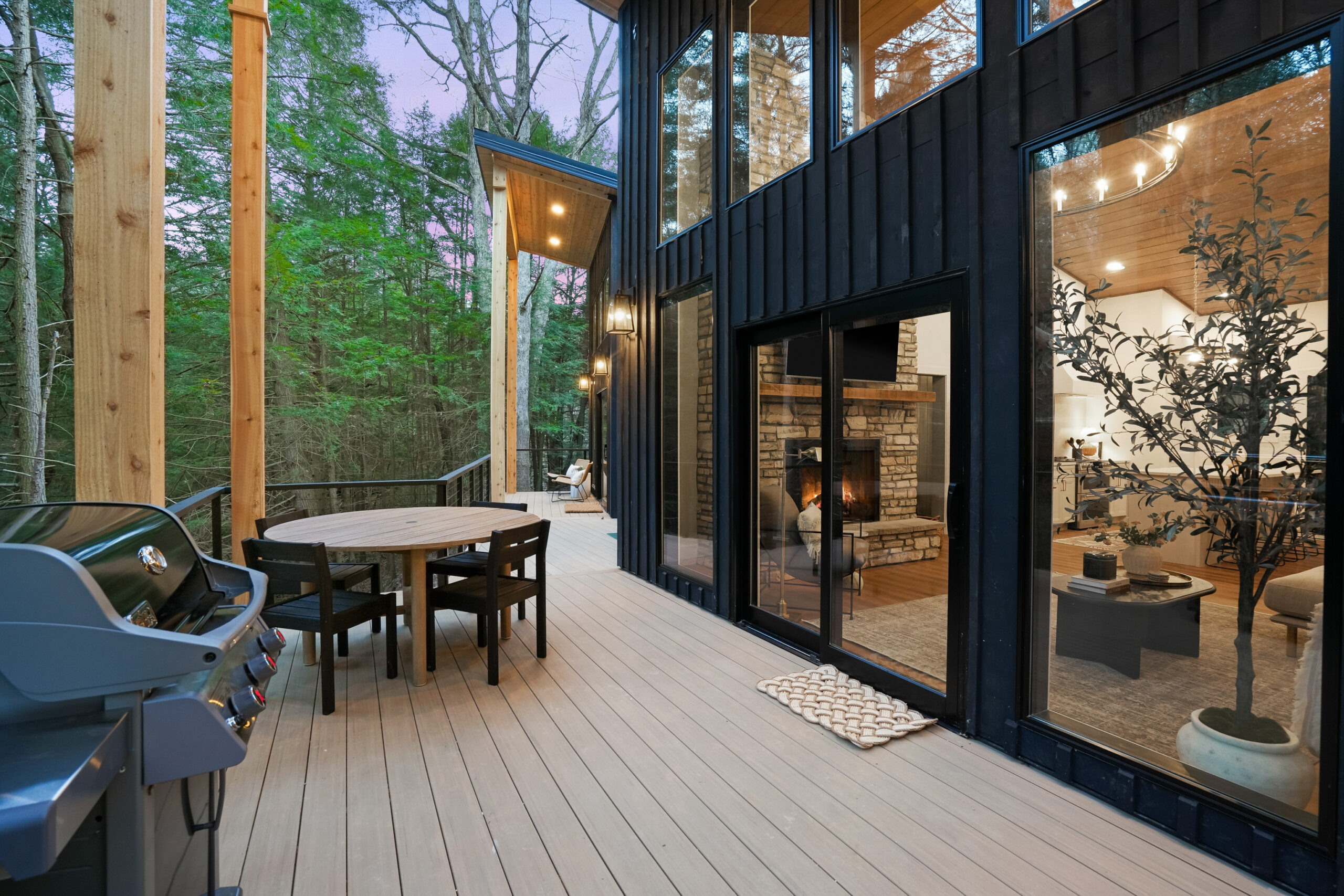 grill and a round table with black chairs outside of the cabin