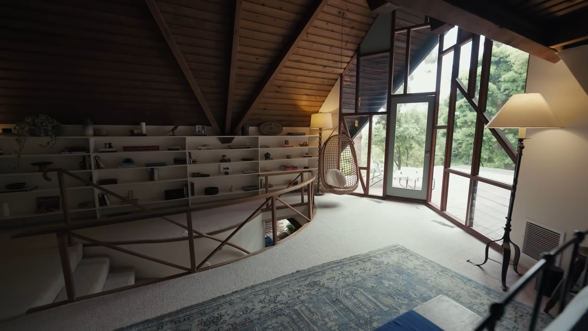 hanging chair between a floor to ceiling window which is framed and a big white shelf