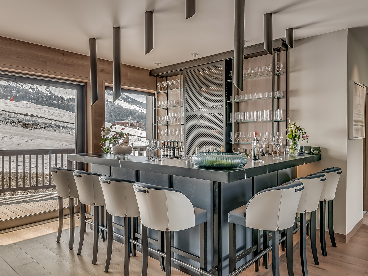 home bar with a black table, bar stools and open shelves with glasses