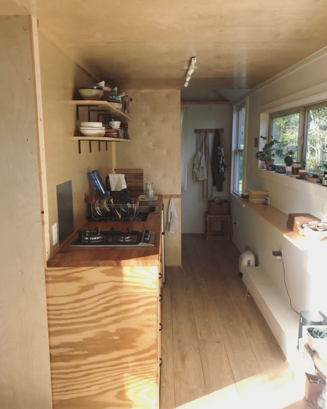 kitchen with a wooden countertop with shelves above it and a mini countertop on the opposite side with a window above it