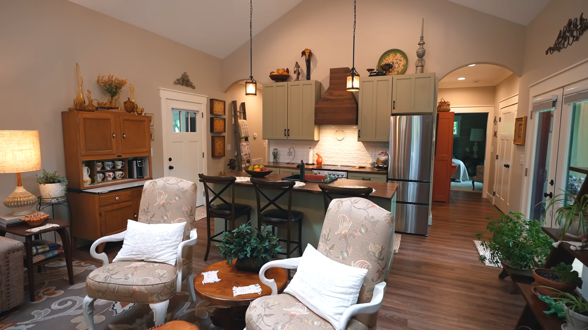 kitchen with light green cabinets and a brown countertop, a brown cabinet on the side and three bar stools