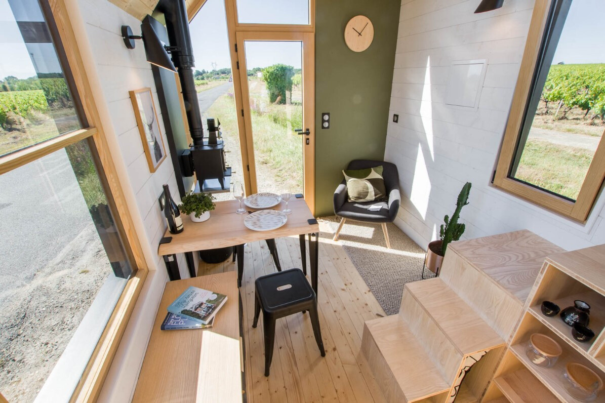 living area with a brown table, black chair in the corner and windows on both sides