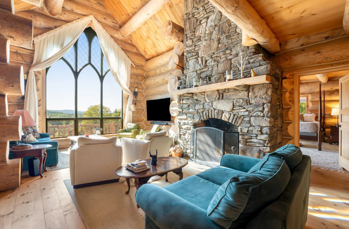 living room with a blue couch and an oval brown table and more sofas in the back next to the window