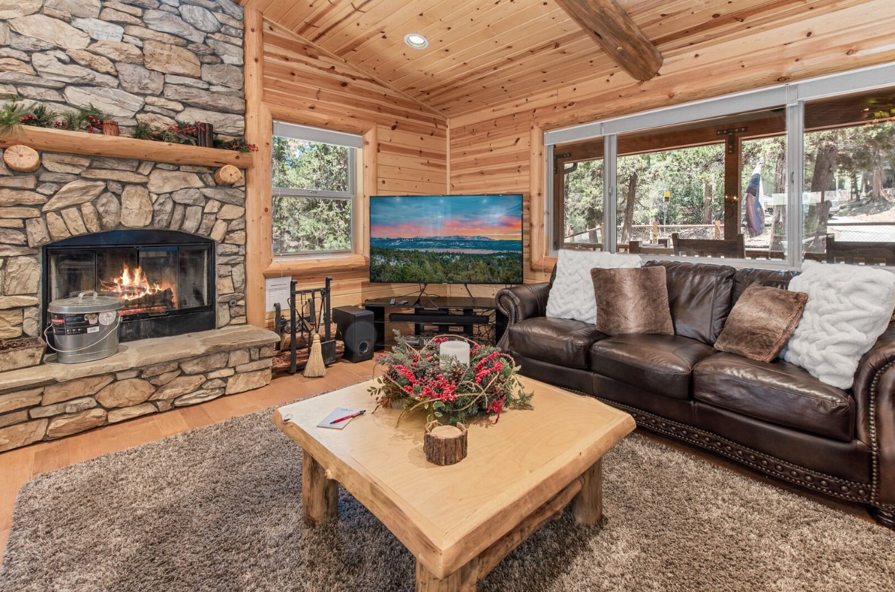 living room with a brown couch, wooden table, brown walls and a fireplace and a flat screen tv