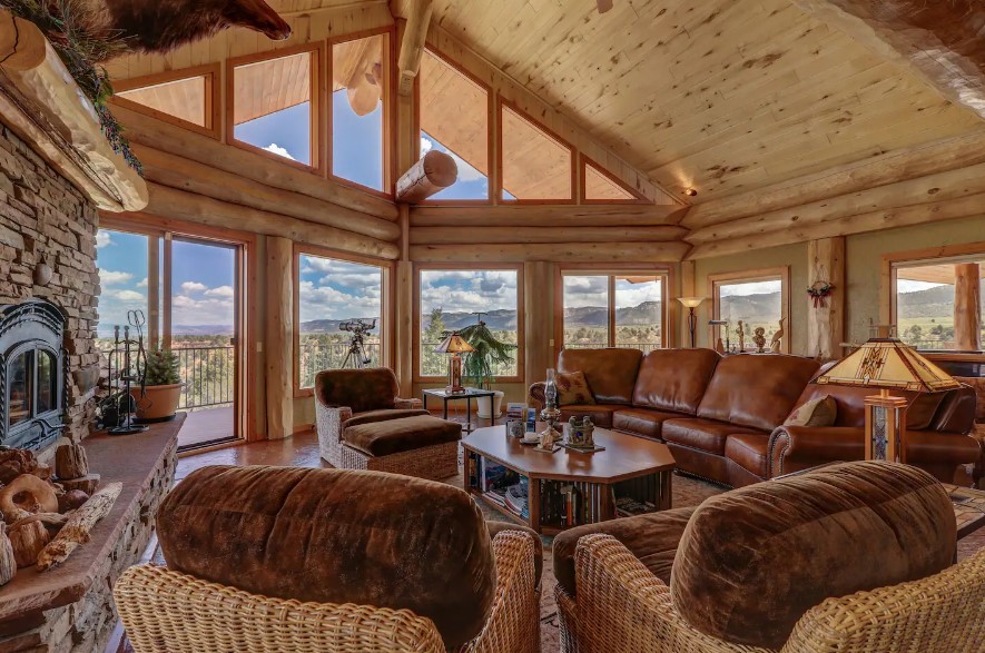 living room with a floor to ceiling windows and brown leather couches and a fireplace