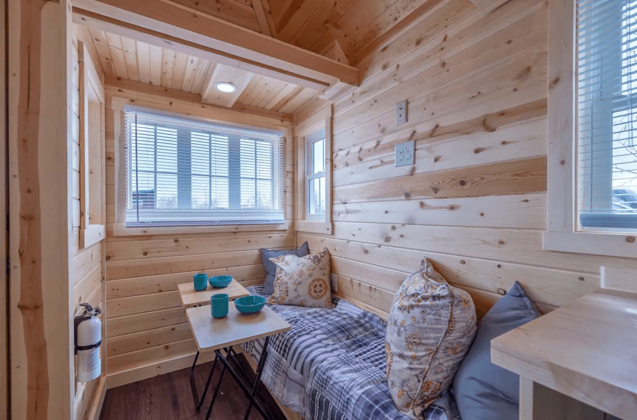 living room with wooden walls and a built in furnished bench and windows all around