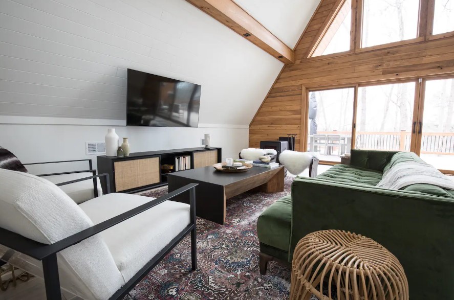 living room with a dark green couch, white cushioned sofa, flat screen tv, dark brown table and big windows