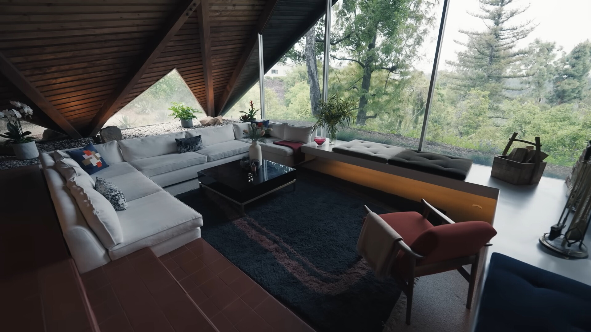 living room with a floor to ceiling window, an l-shaped white couch and dark brown wall and black table