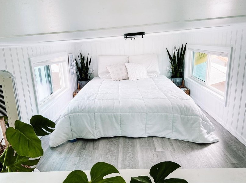 loft bedroom with a bed, two windows, white walls