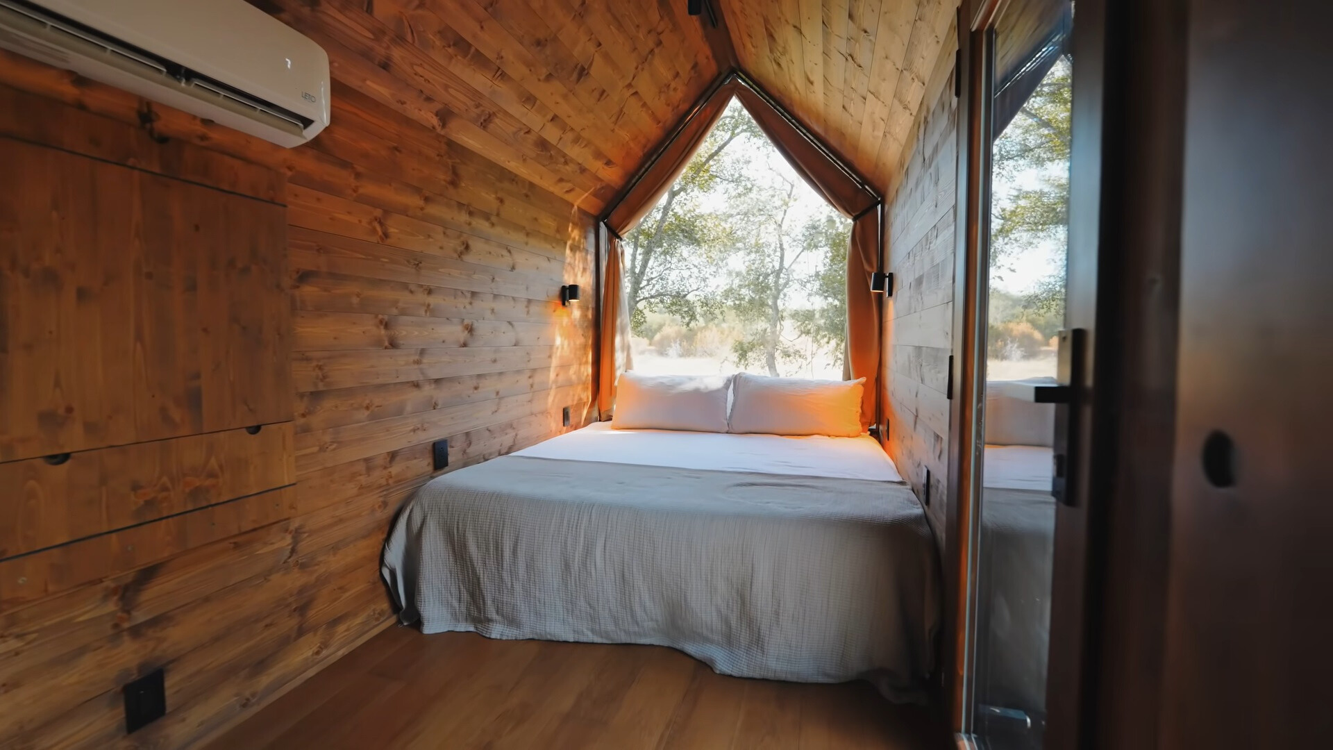 primary area of the tiny home, a nook like room with a bed and a floor to ceiling window