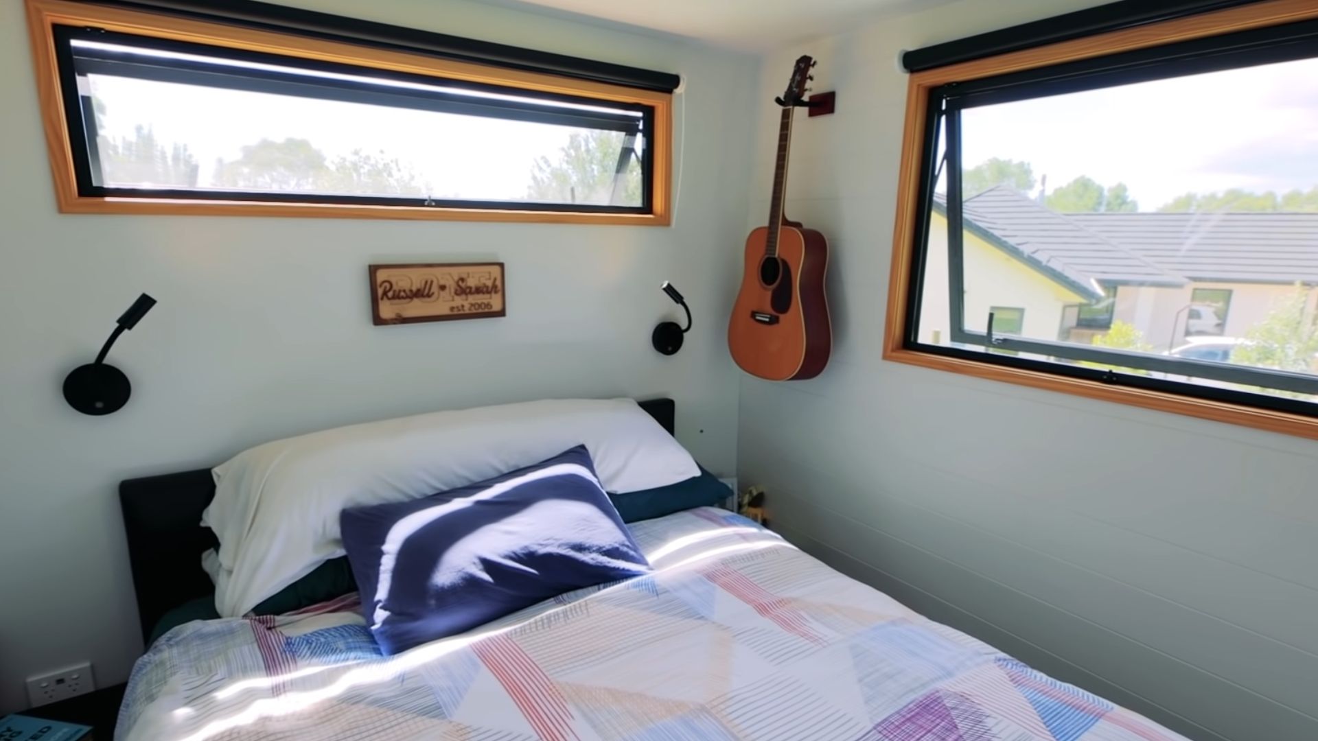 parents' bedroom with a comfy bed in the middle, a guitar on the wall, and two window letting in plenty of natural light