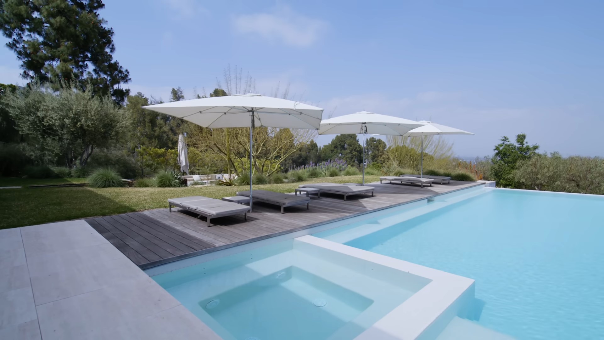 Pool with a wooden lounge area and built in hot tub