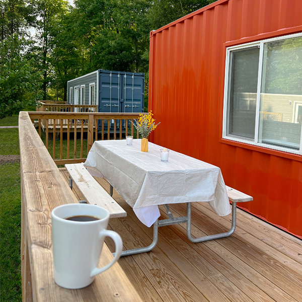 porch of a red container house with a table and benches on it