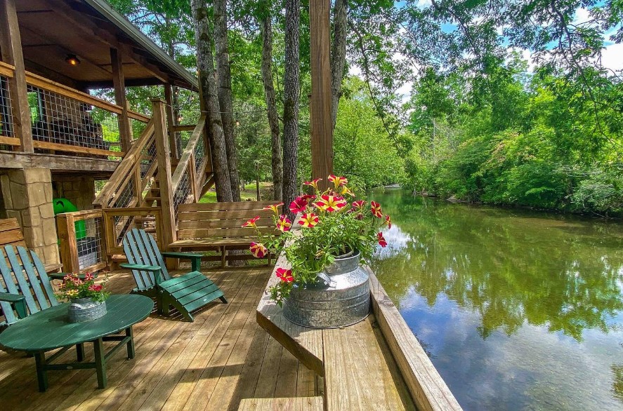 terrace with green chairs and a green table with a view of the river and the trees