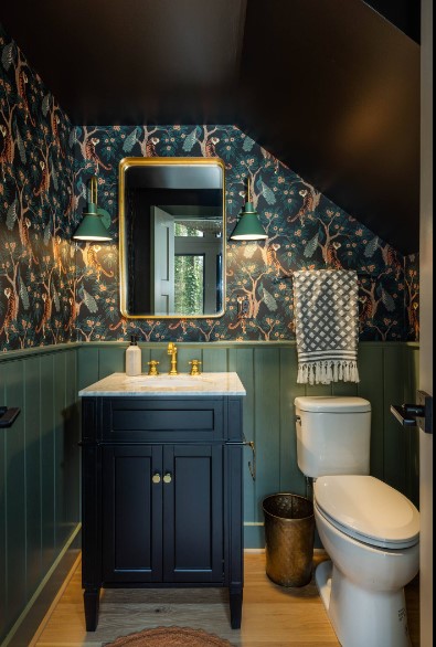 toilet with a half green-half texture wall, golden faucet and a golden mirror