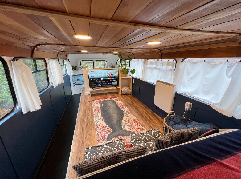 flat screen tv in the bedroom on the second floor of the double decker bus with windows all around