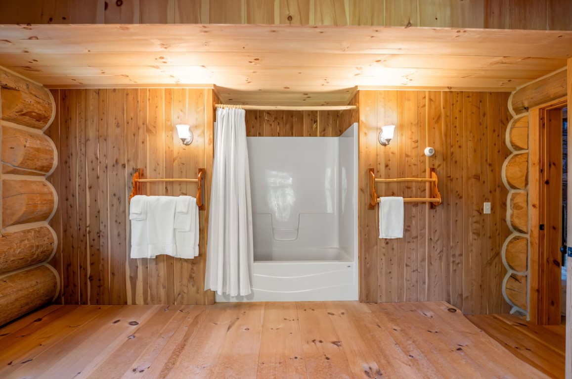 bathroom with wooden walls and a white bathtub with a white curtain