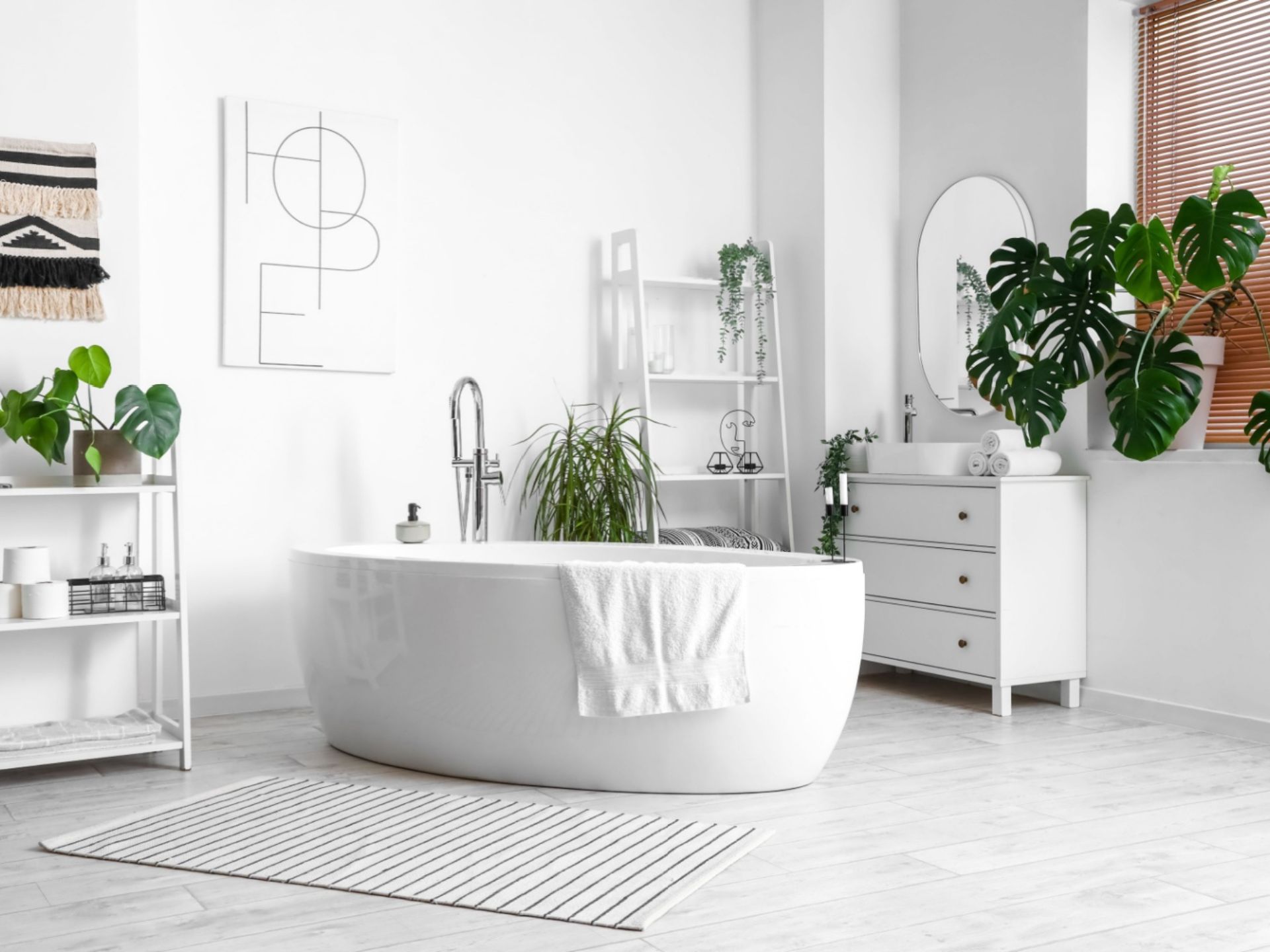 bathroom with a white wall, white bathtub in the middle, white cabinet and white shelves, green plants