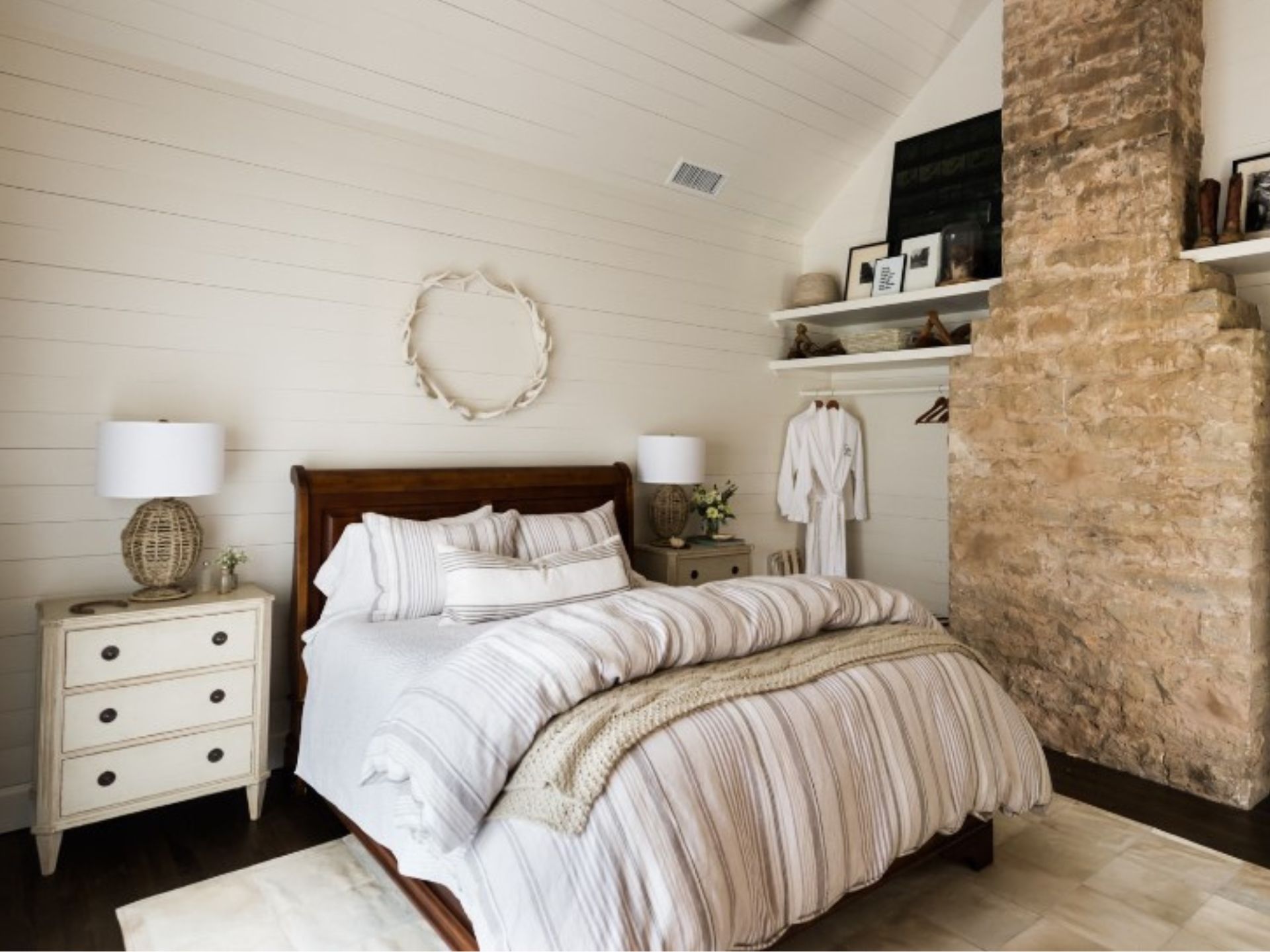 bedroom with a wooden white wall, white bedside table, brown bed frame of a comfy bed