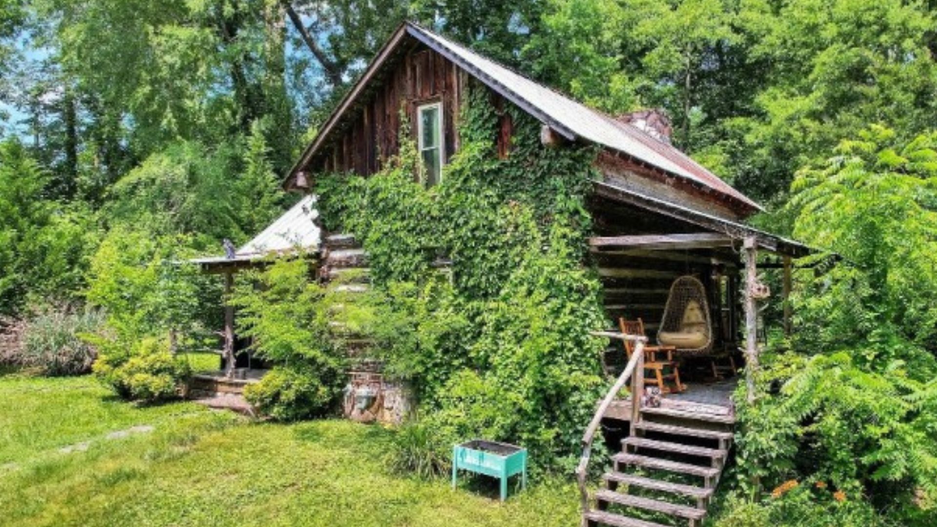 exterior of an old cabin, trees and grass around