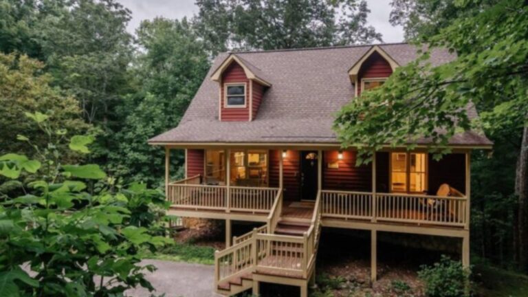 Red wooden cabin with large deck in the woods