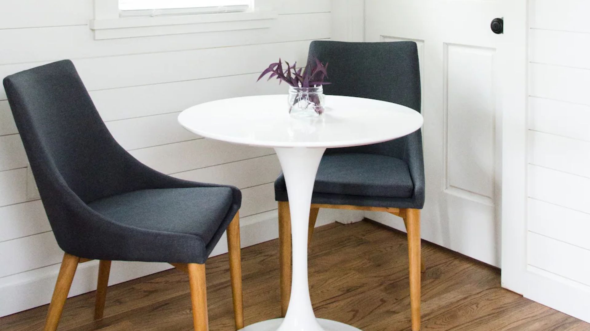 dinin nook with a white round table and two sleek grey chairs