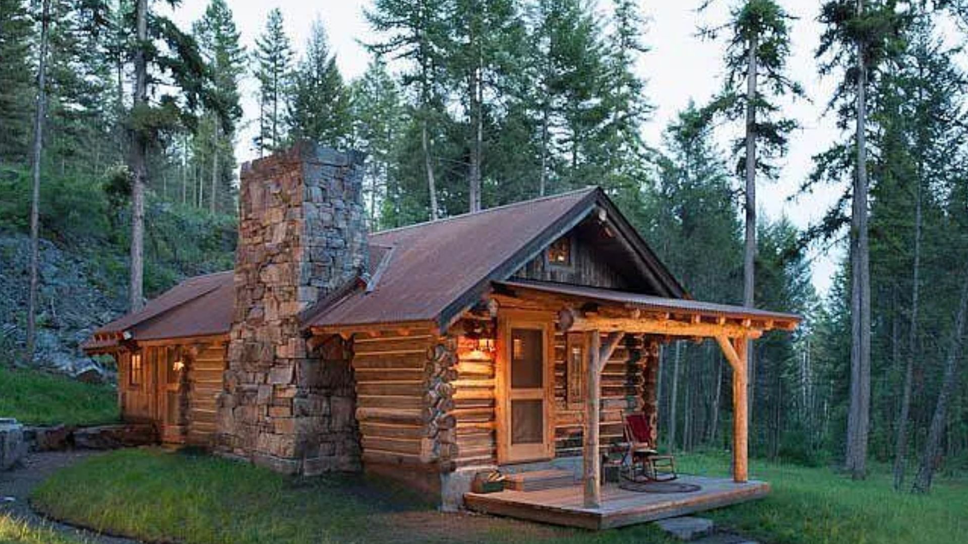 exterior of a log cabin with a small porch and lights on