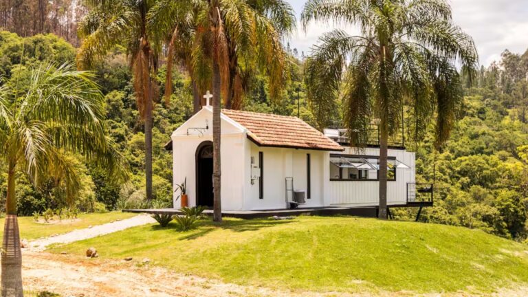 exterior of a chapel turned container, white walls, palms around it