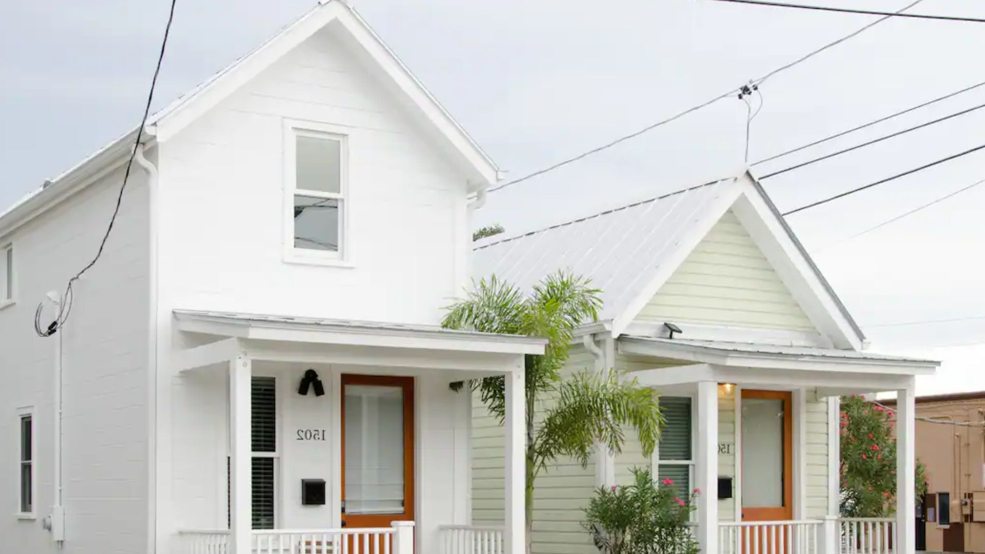 Two white similar houses, next to each other, with small porch