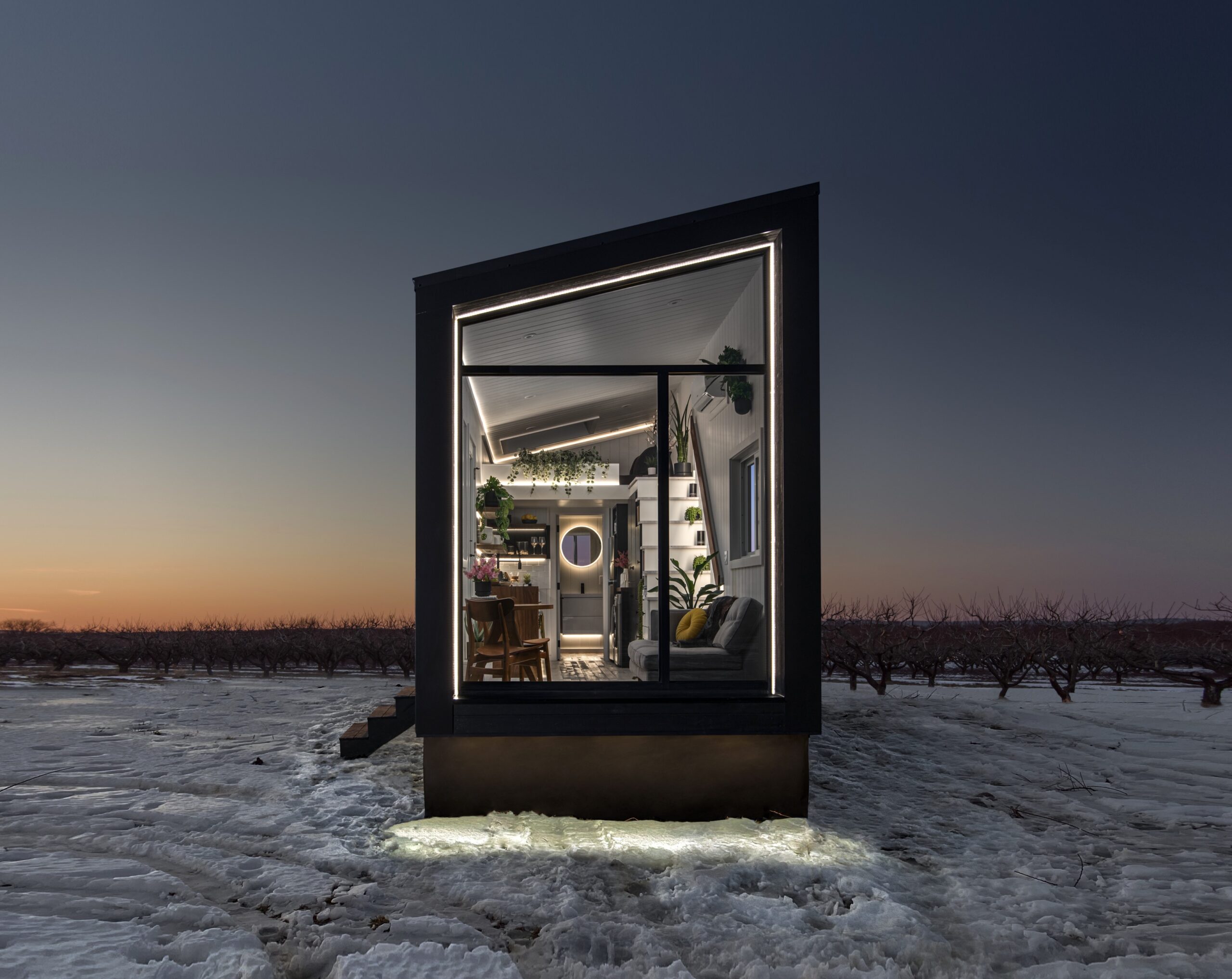 Exterior of a tiny black home with a huge window and LED lights