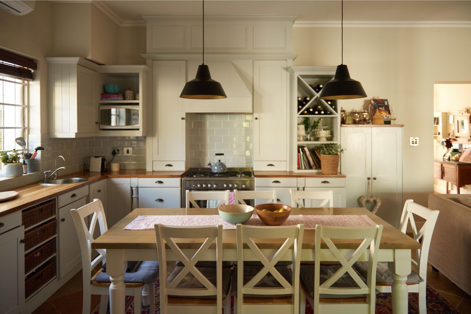 Family kitchen with a light color scheme and lights above the dining table