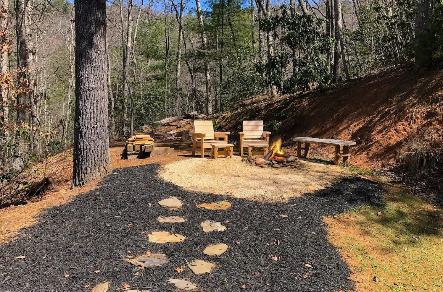 A fireplace in the woods with two armchairs and a bench