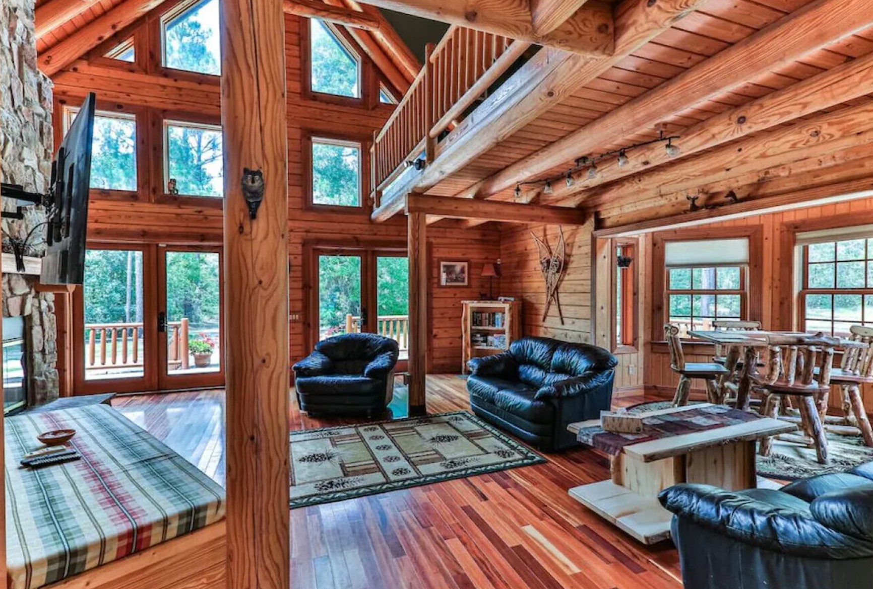 Wooden living room with black couches and a rug