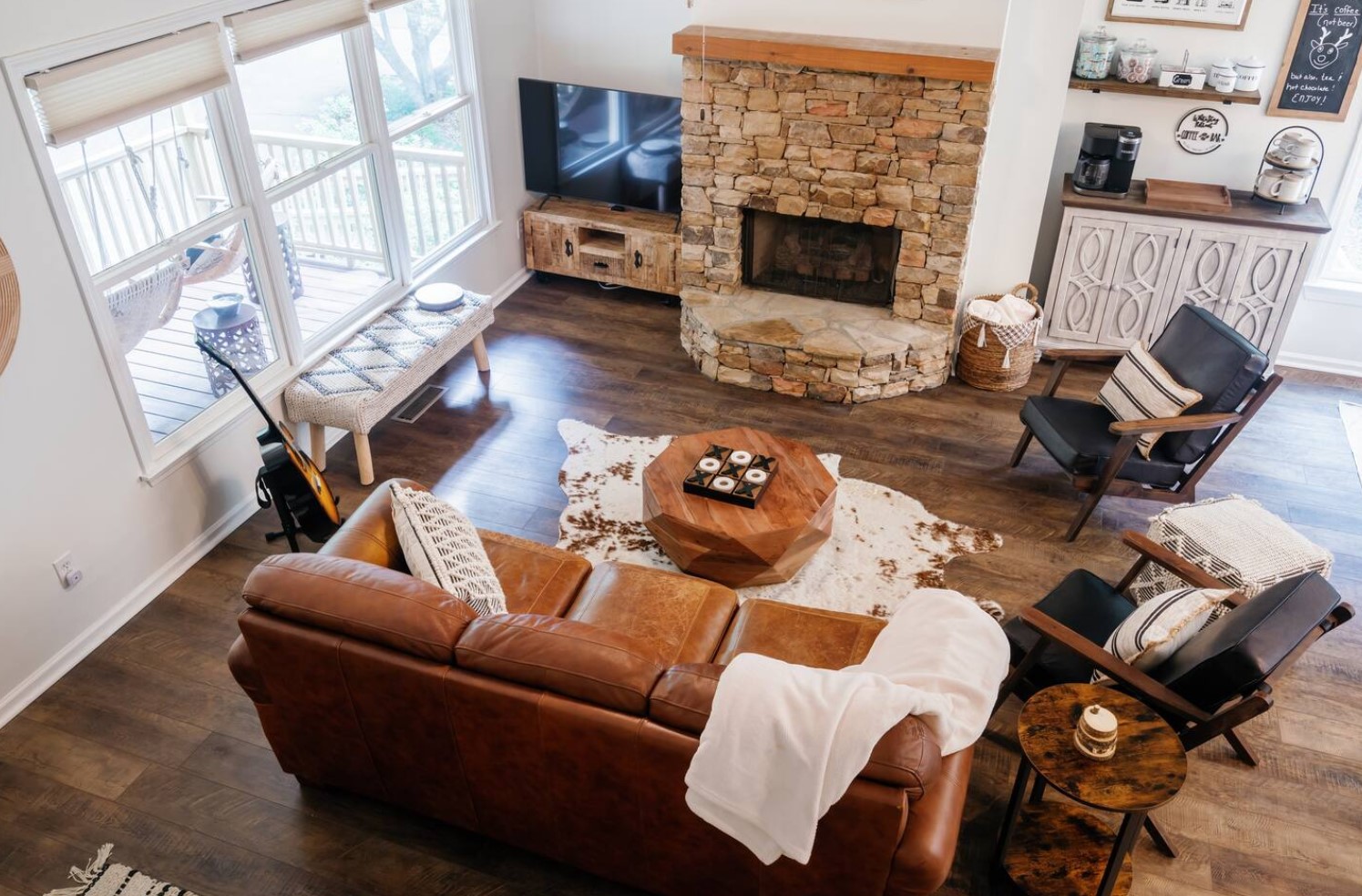 Living room with a stone fireplace, leather couch and a coffee station