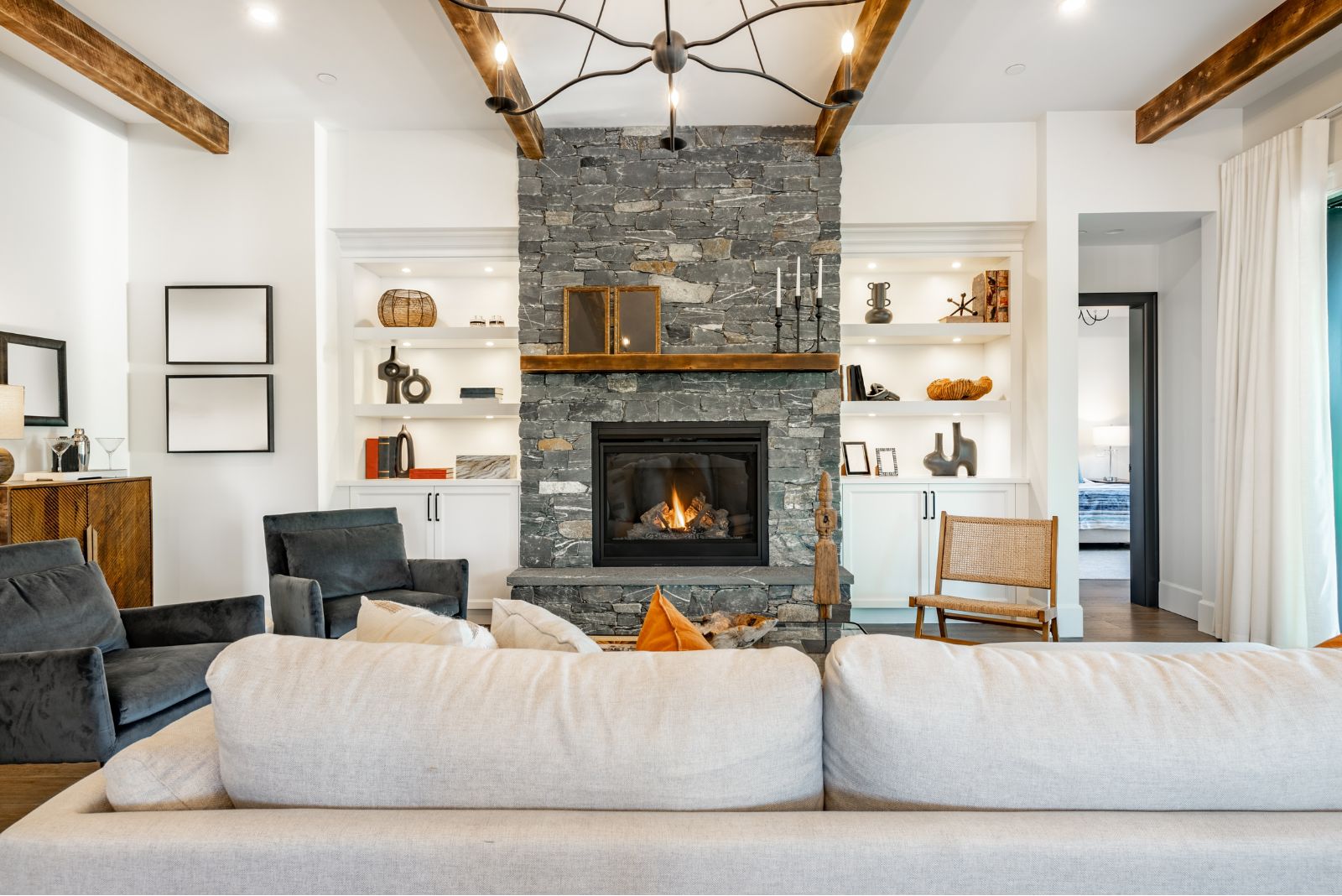 Living room with a white couch, stone fireplace and wooden beams on ceilings