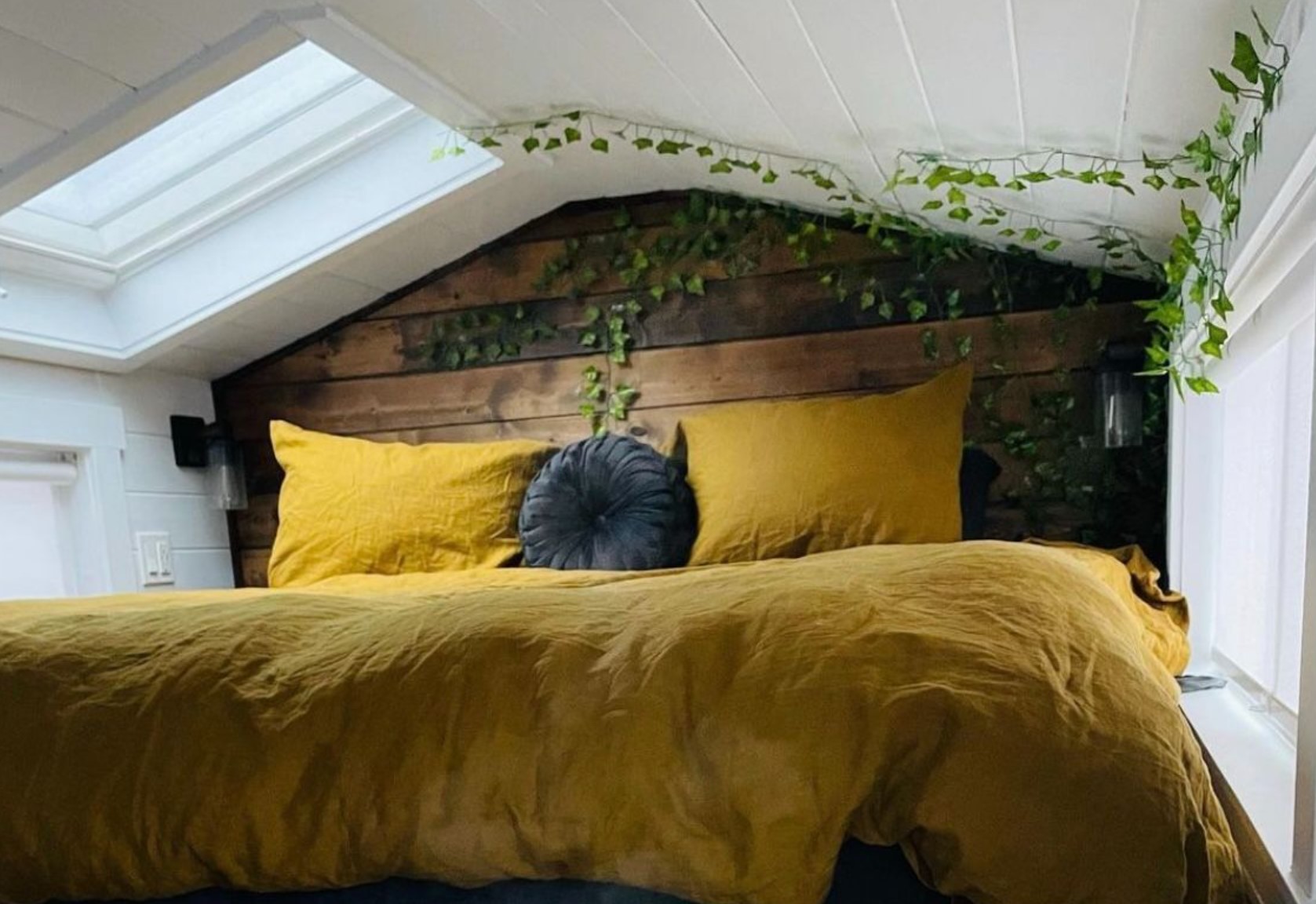 Loft bedroom with yellow bedding and plants