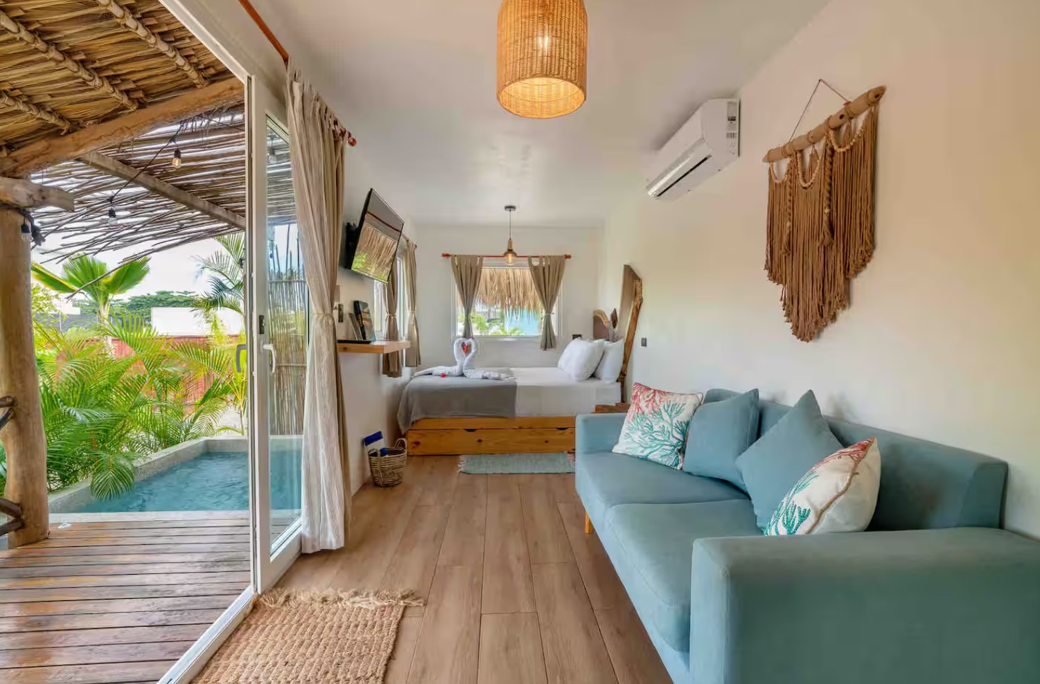 Open concept living room with a blue couch and a bedroom at the back