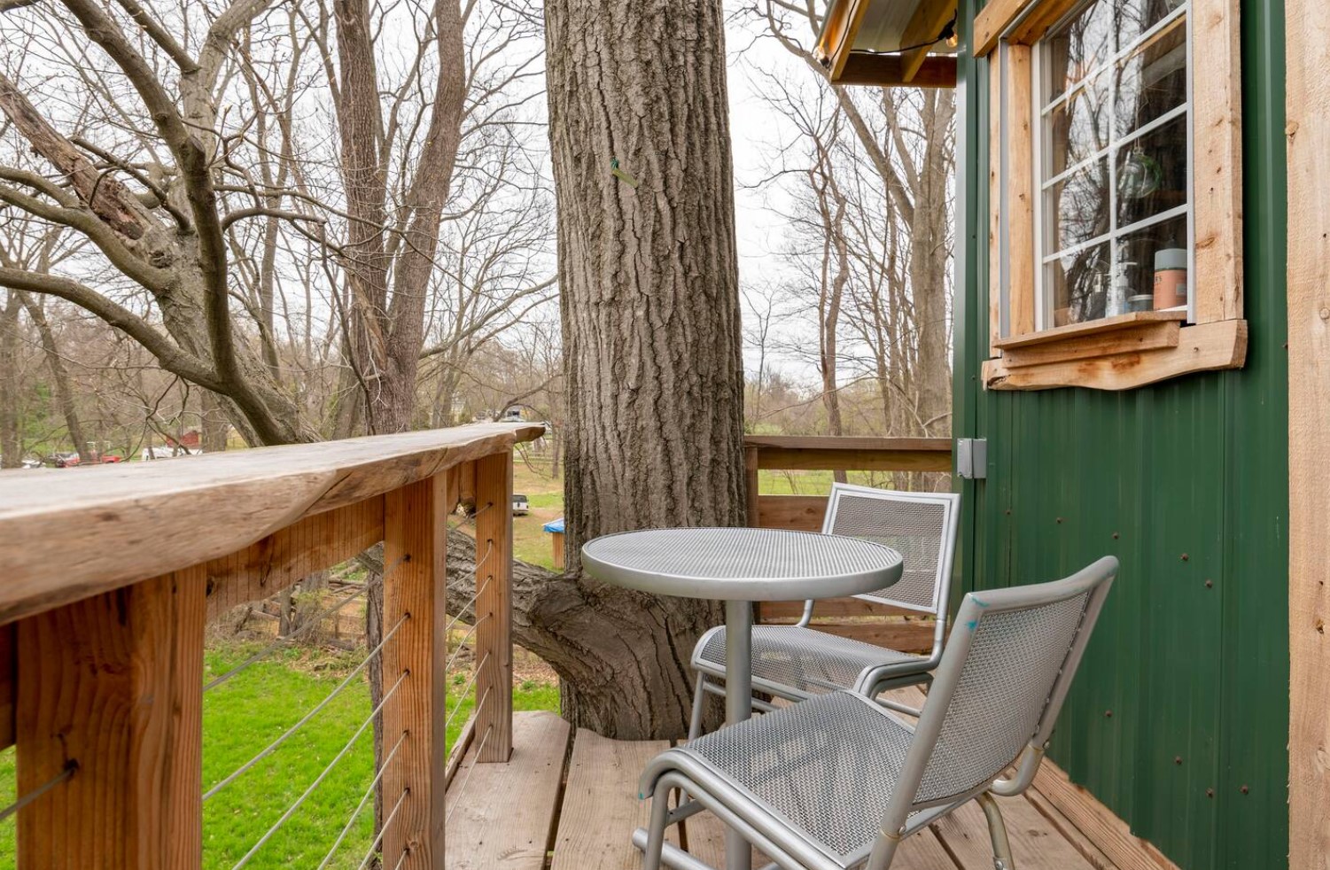 Patio of a green tree house with metal table and chairs