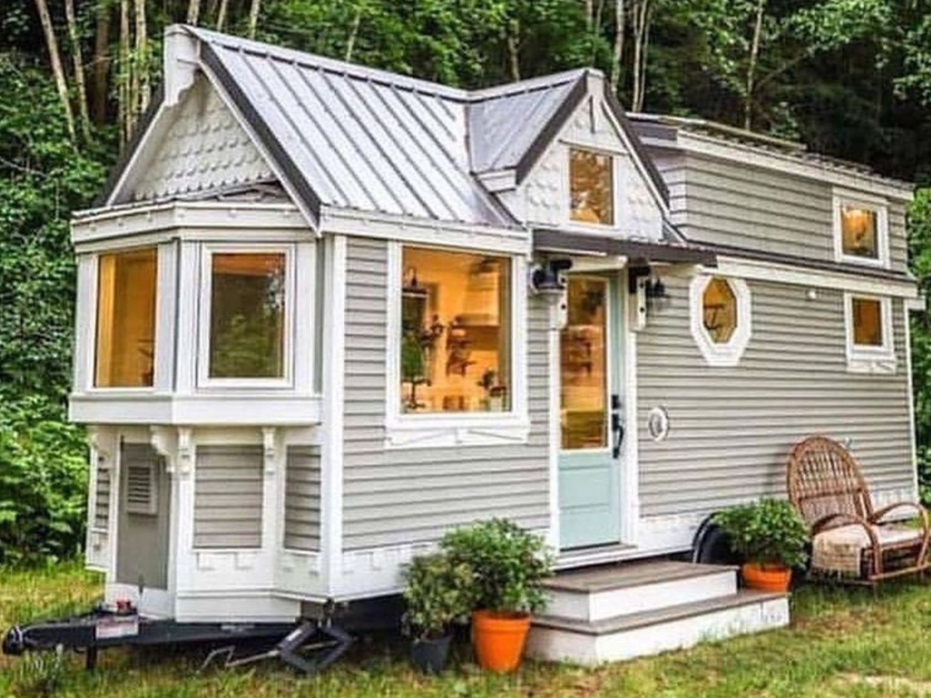 exterior of the light grey THOW with white frames around windows, lots of cool gable work