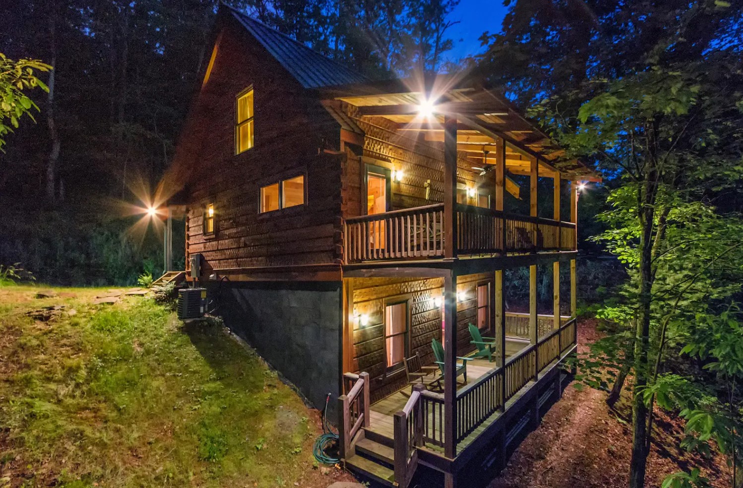 The back of a two story cabin that is lit up