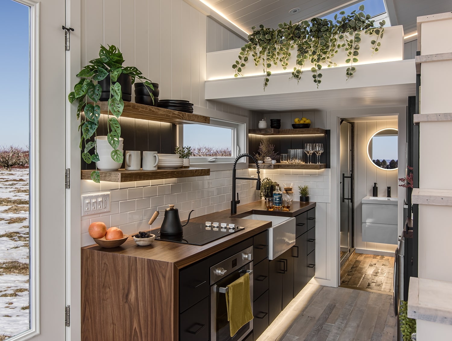 Tiny wooden kitchen with black cabinets and shelves