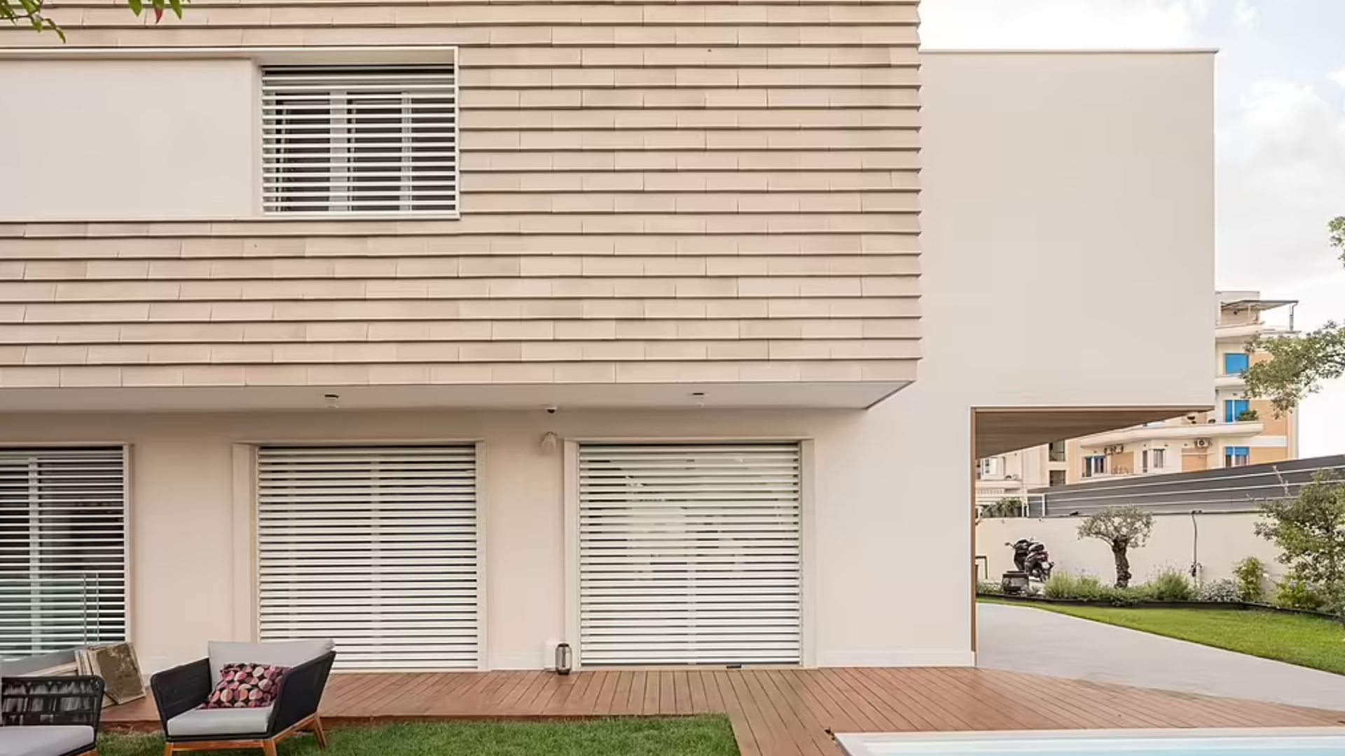 exterior of a modern house, a pool and deck chairs around it