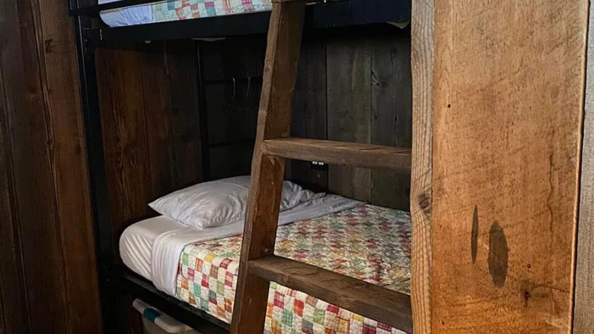 rustic bunk bed with a wooden ladder in the cabin