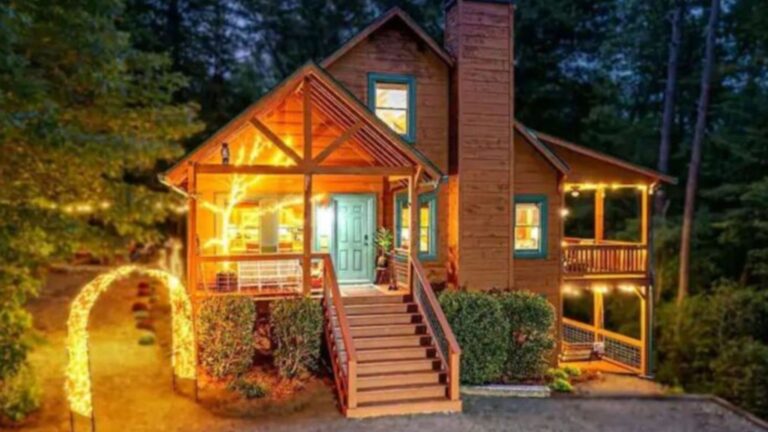 exterior of the cabin with a dominant staircase and chimney next to it, lots of string lights and lamps around the property