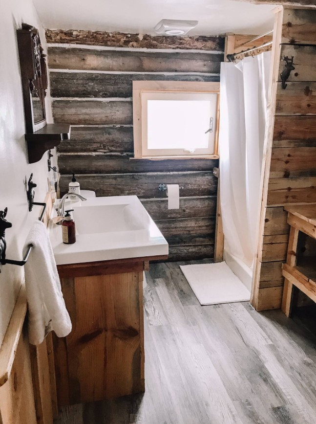 bathroom with brown wooden walls, brown cabinet, white sink and white shower curtain