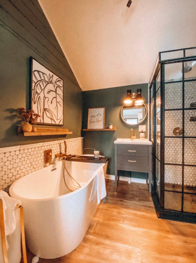 bathroom with a half green and half white tiled walls, white bathtub and a glass shower