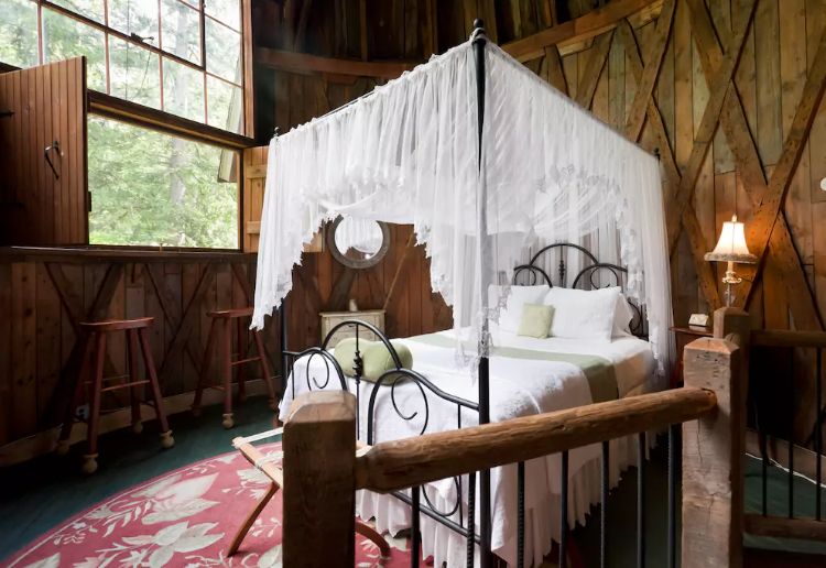 bedroom with a canopy bed, window with two wooden a bar stools